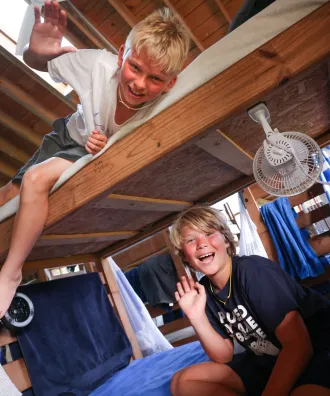 One boy on the top bunk and one boy waving from bottom bunk