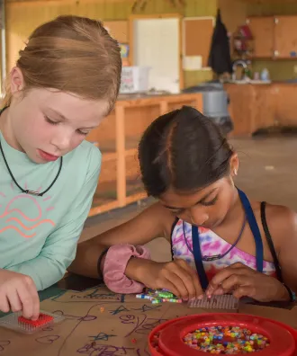Two girls creating pearler bead artwork