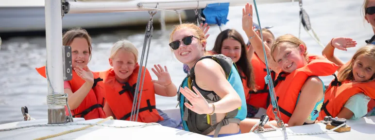 Girls waving at the camera from the sailboat