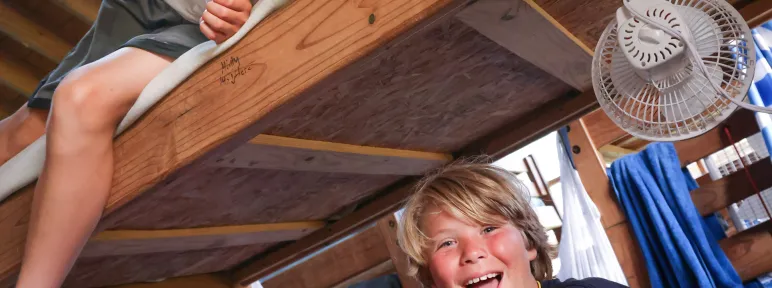 One boy on the top bunk and one boy waving from bottom bunk