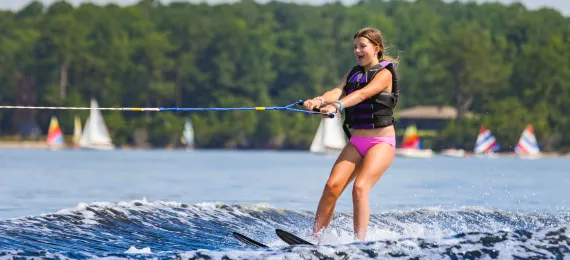 Girl waterskiing with sailboats in the background