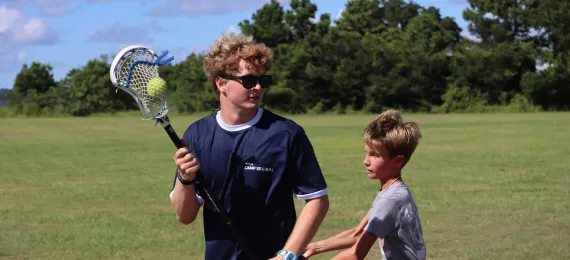 Counselor and boy playing lacrosse