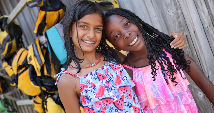 Two girls near the lifejacket rack for camp