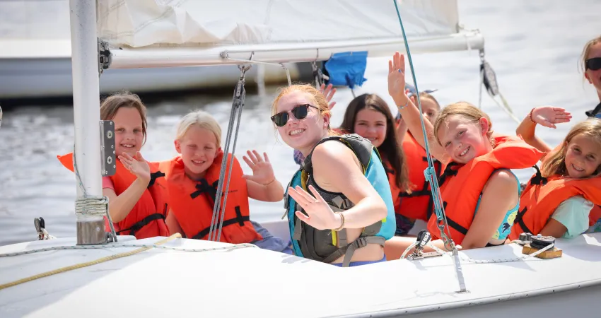 Girls waving at the camera from the sailboat