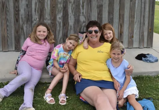 Group of girls out side their cabin surrounding Seafarer Mother Duck volunteer.